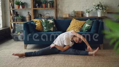 苗条的亚洲女士在家里做运动，伸展身体、手臂和腿，坐在地板上，享受活动